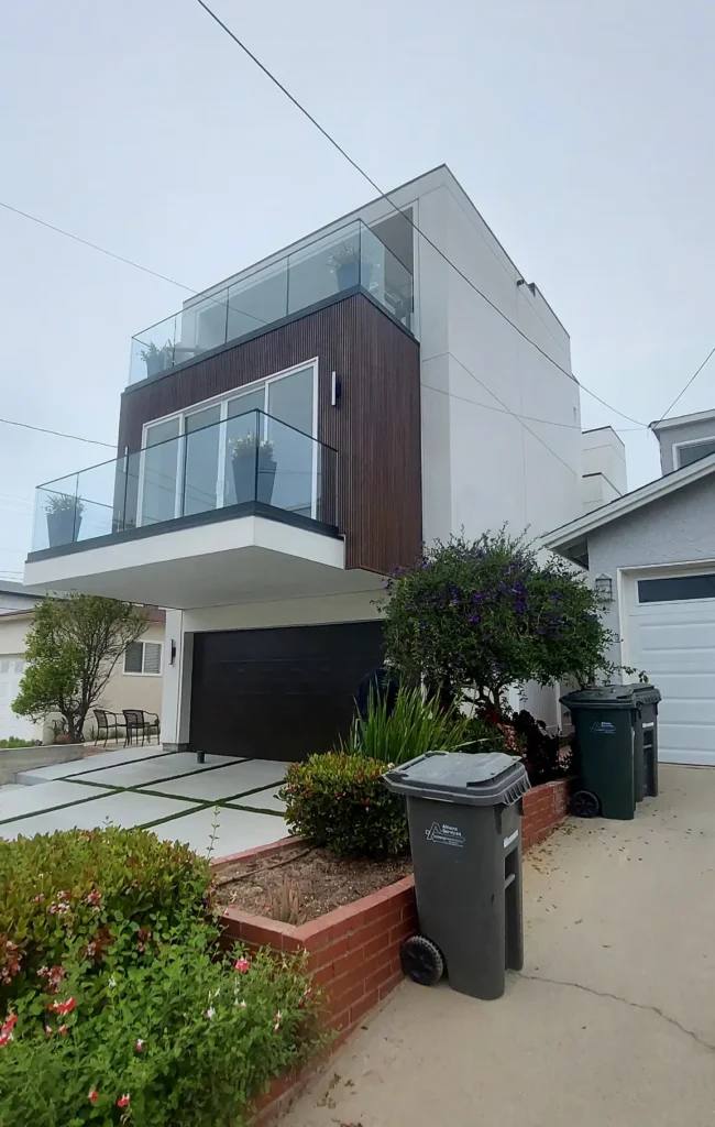 Modern three-story home facade with glass railings and wood panel accents
